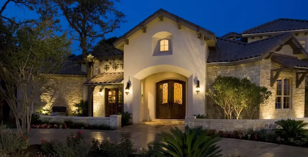 A beautifully illuminated modern home at night, featuring warm outdoor lighting and a cozy ambiance